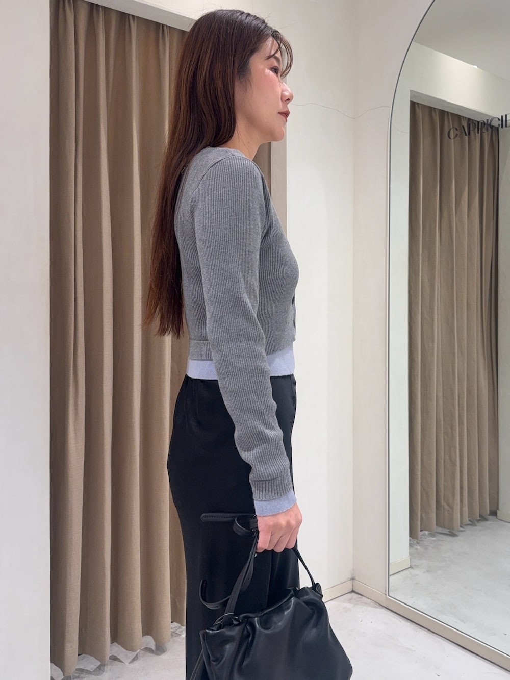 グレー系のカーディガン/ボレロ、ブラック系のスカート、ブラック系のショルダーバッグを着用したレディースの冬コーディネートの5枚目の写真