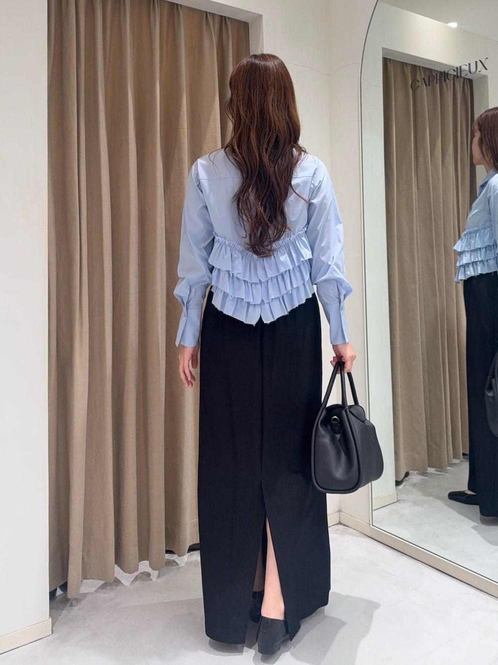 ブルー系のシャツ/ブラウス、ブラック系のショルダーバッグ、ブラック系のスカートを着用したレディースの冬コーディネートの4枚目の写真