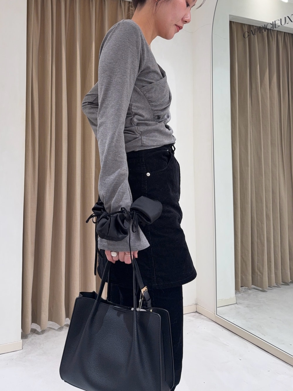 グレー系のTシャツ/カットソー、ブラック系のスカート、ブラック系のトートバッグを着用したレディースの冬コーディネートの4枚目の写真