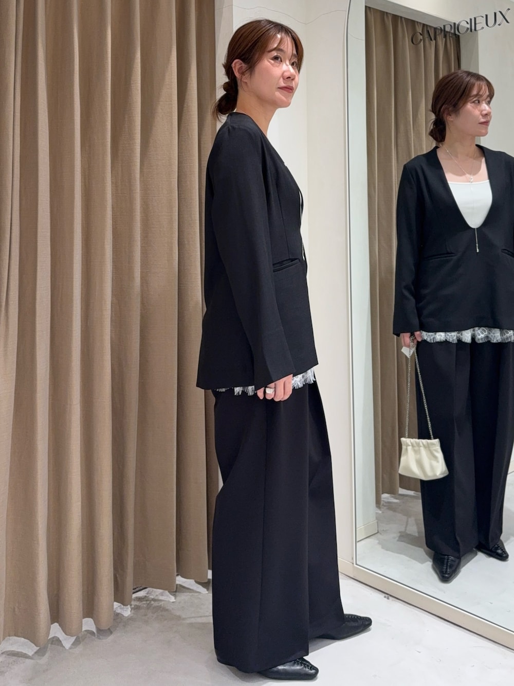 ブラック系のトップス、ホワイト系のキャミソール、ホワイト系のショルダーバッグを着用したレディースの春コーディネートの3枚目の写真