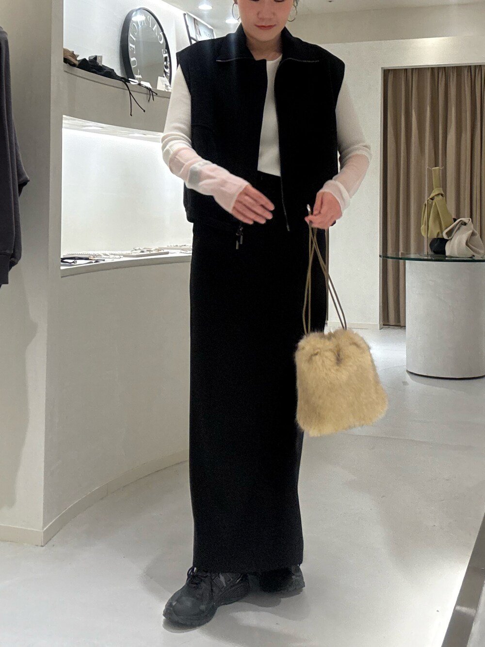 ブラック系のベスト、ホワイト系のTシャツ/カットソー、ブラック系のスカートを着用したレディースの冬コーディネートの2枚目の写真