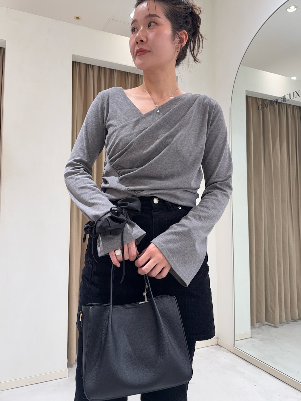 グレー系のTシャツ/カットソー、ブラック系のスカート、ブラック系のトートバッグを着用したレディースの冬コーディネートの3枚目の写真