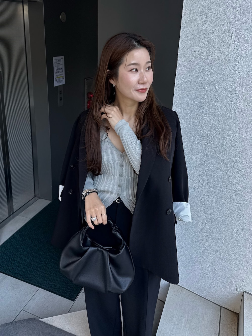 ブラック系のテーラードジャケット、グレー系のカーディガン/ボレロ、ブラック系のショルダーバッグを着用したレディースの冬コーディネートの5枚目の写真