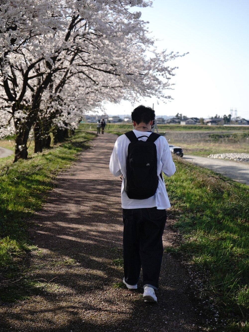 ホワイト系のTシャツ/カットソー、ブラック系のデニムパンツ、ホワイト系のスニーカーを着用したメンズの春コーディネートの2枚目の写真