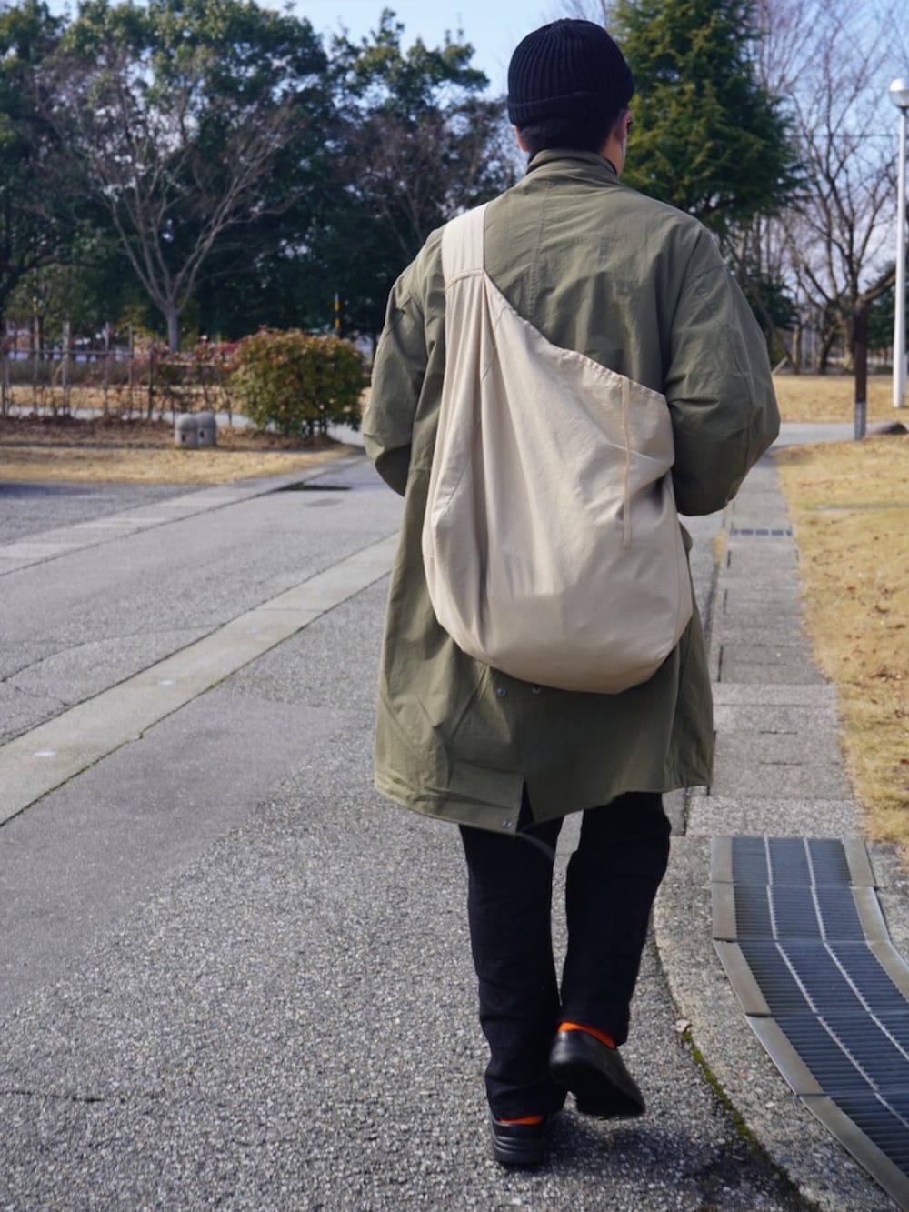 ベージュ系のバッグ、グリーン系のモッズコート、ブラック系のつなぎ/オールインワンを着用したメンズの冬コーディネートの2枚目の写真