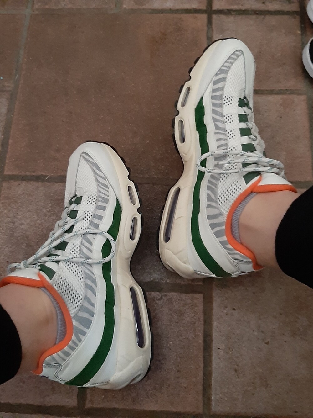 ブラック系のTシャツ/カットソー、ブラック系のスラックス、ホワイト系のスニーカーを着用したメンズの夏コーディネートの2枚目の写真