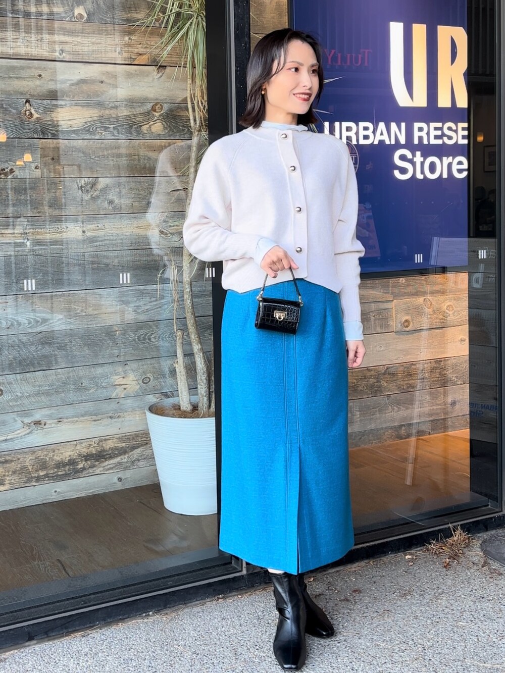 ブルー系のTシャツ/カットソー、ブラック系のショルダーバッグ、ブラック系のブーツを着用したレディースの冬コーディネートの2枚目の写真