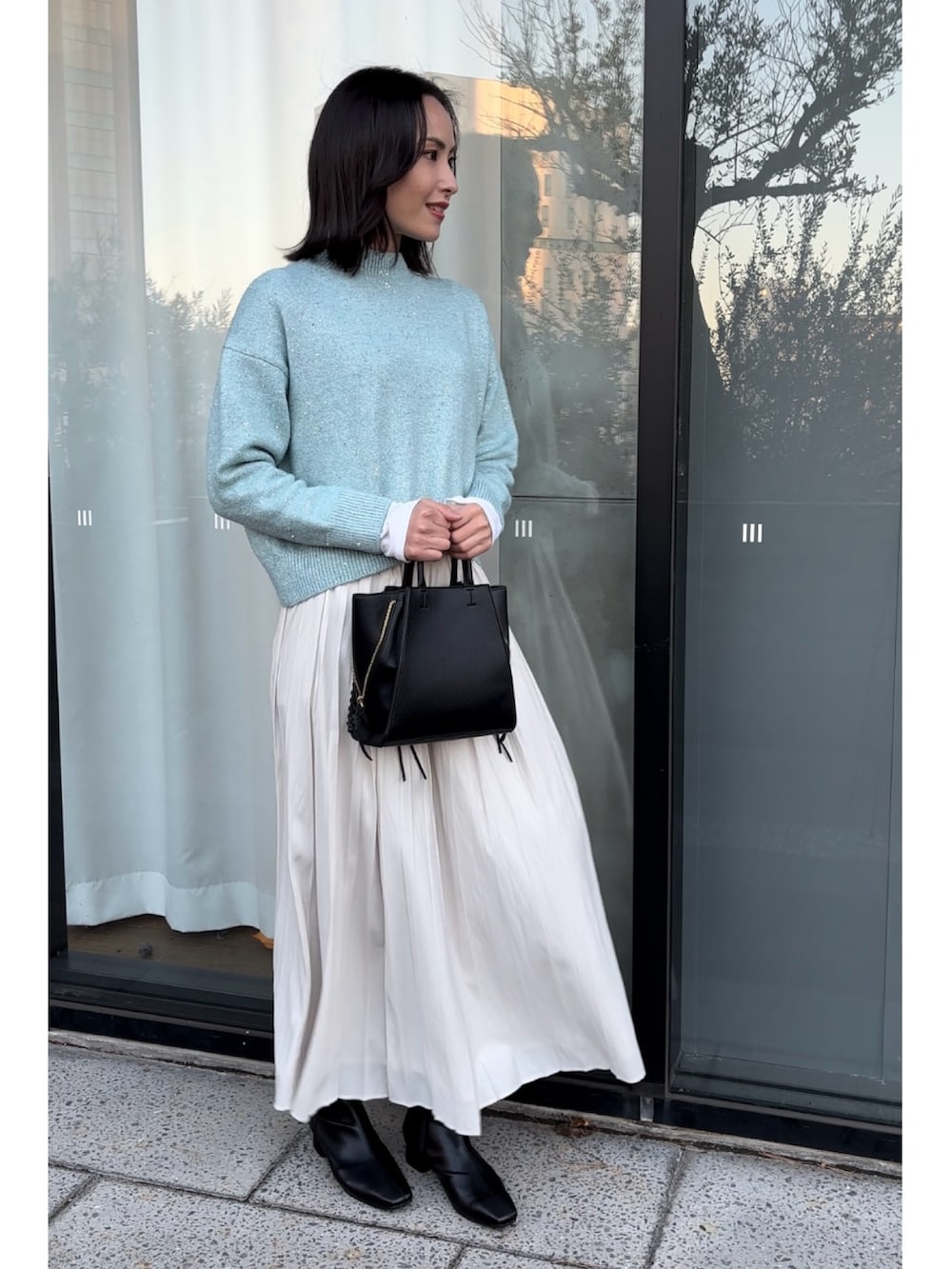 ブルー系のニット/セーター、ブラック系のショルダーバッグ、ホワイト系のスカートを着用したレディースの秋コーディネートの5枚目の写真