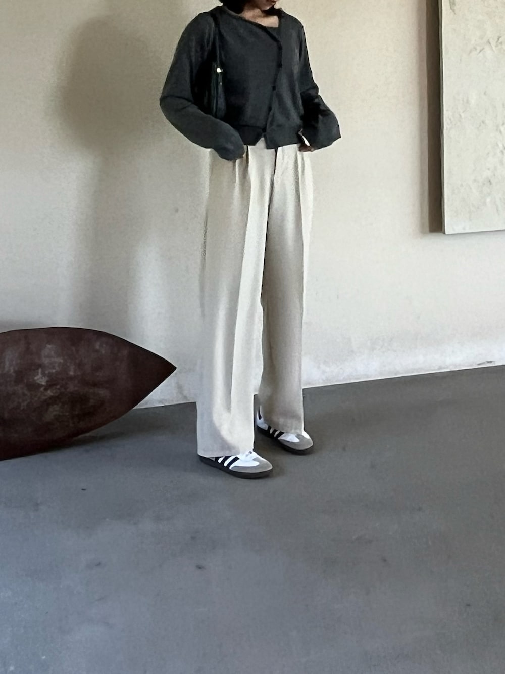 ホワイト系のスニーカー、ブラック系のハンドバッグ、グレー系のカーディガン/ボレロを着用したレディースの冬コーディネートの2枚目の写真