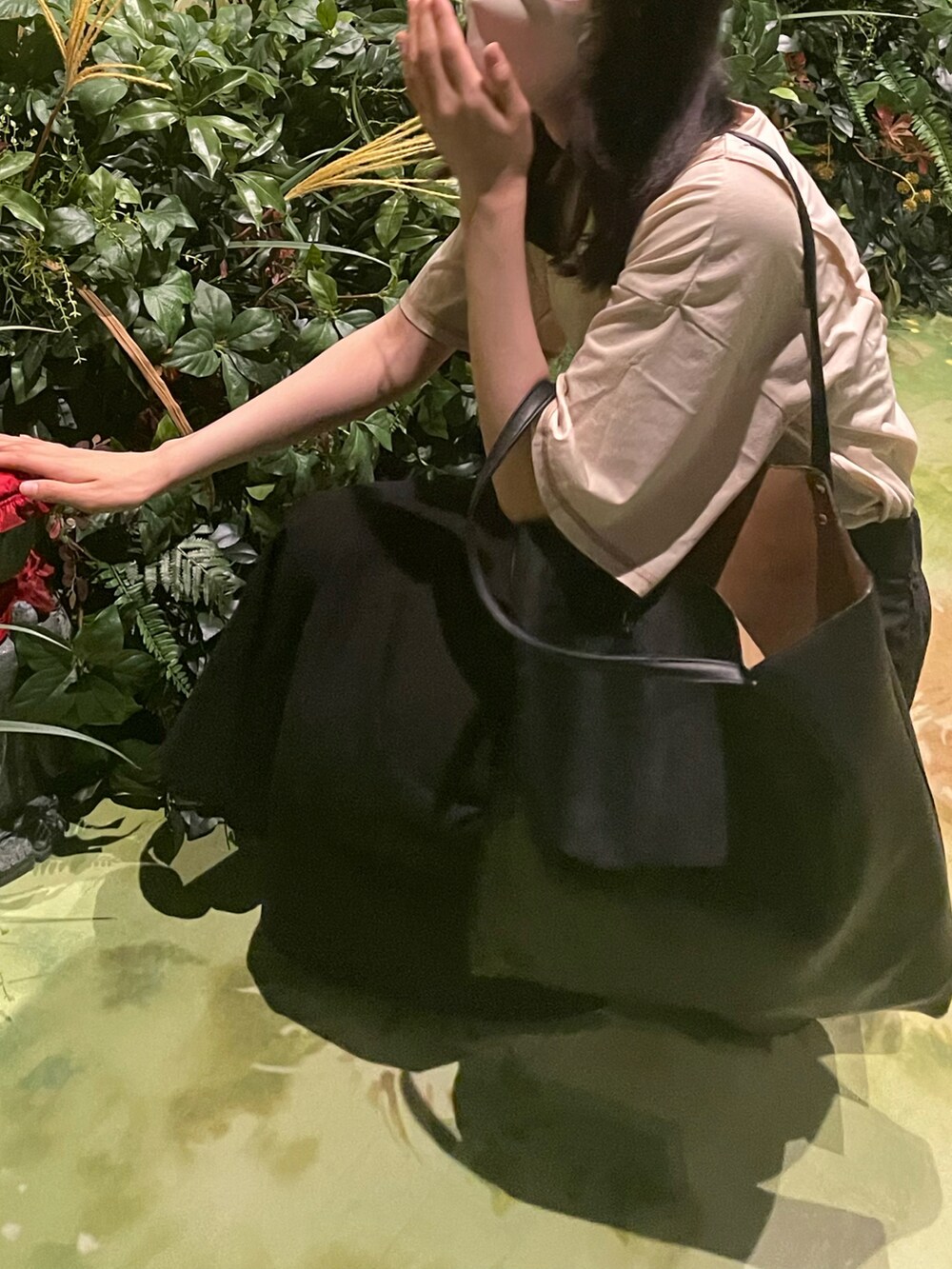 ブラック系のスカート、ホワイト系のTシャツ/カットソー、ブラック系のスニーカーを着用したレディースの春コーディネートの2枚目の写真