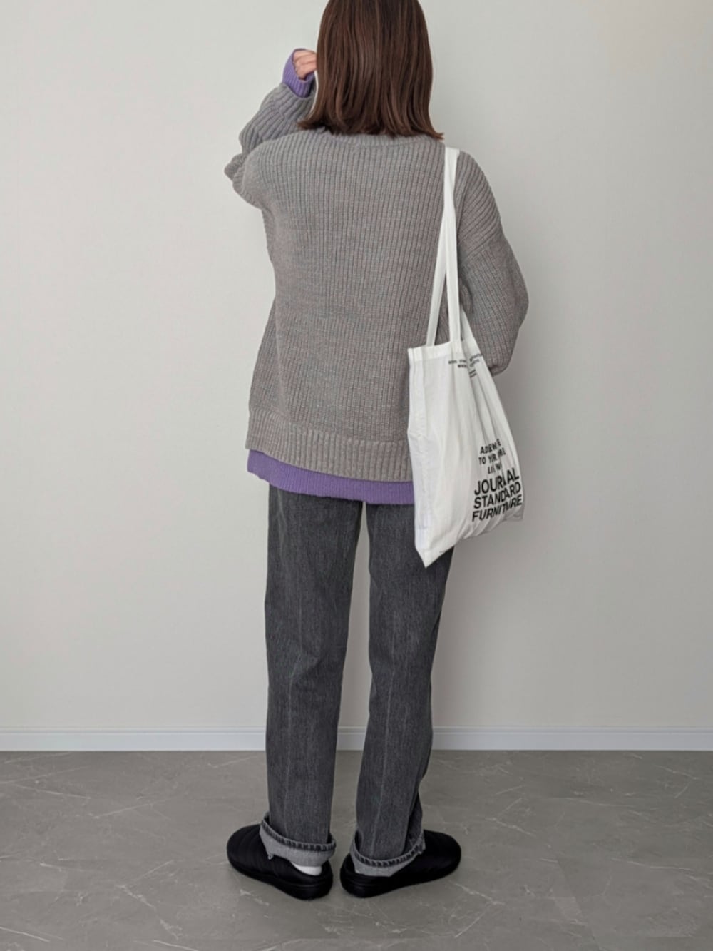 グレー系のニット/セーター、グレー系のデニムパンツ、ブラック系のサンダルを着用したレディースの冬コーディネートの3枚目の写真