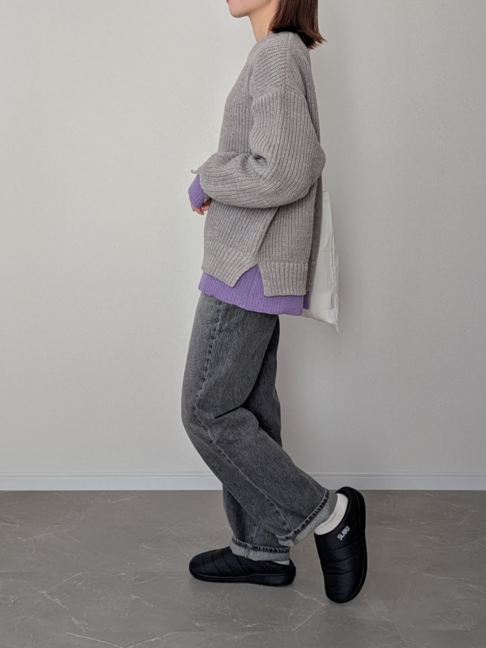 グレー系のニット/セーター、グレー系のデニムパンツ、ブラック系のサンダルを着用したレディースの冬コーディネートの4枚目の写真