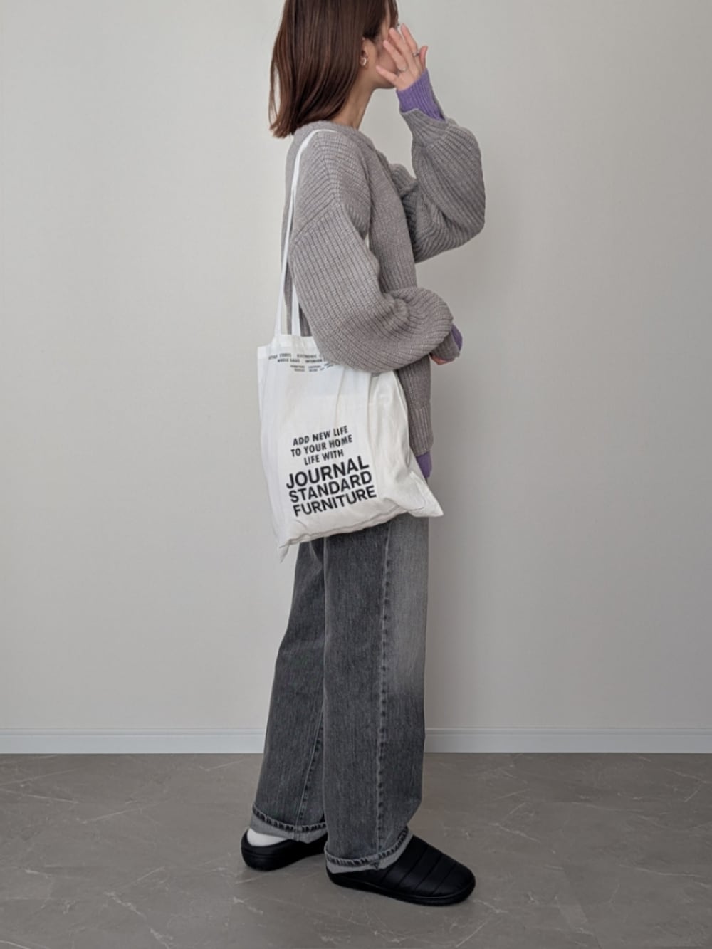 グレー系のニット/セーター、グレー系のデニムパンツ、ブラック系のサンダルを着用したレディースの冬コーディネートの2枚目の写真