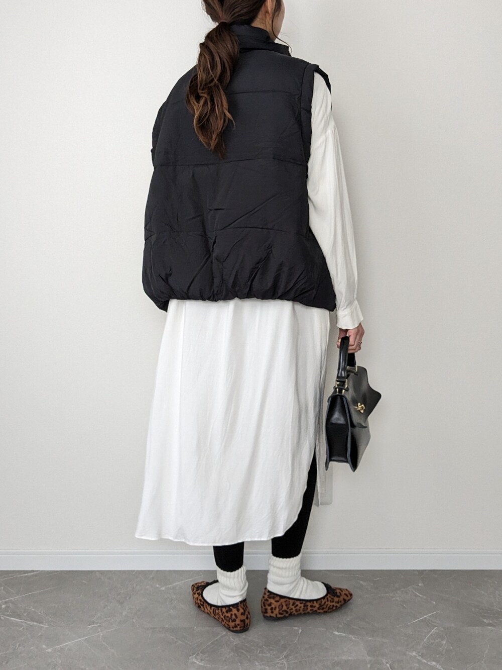 その他のパンプス、ブラック系のショルダーバッグ、ブラック系のダウンベストを着用したレディースの冬コーディネートの2枚目の写真