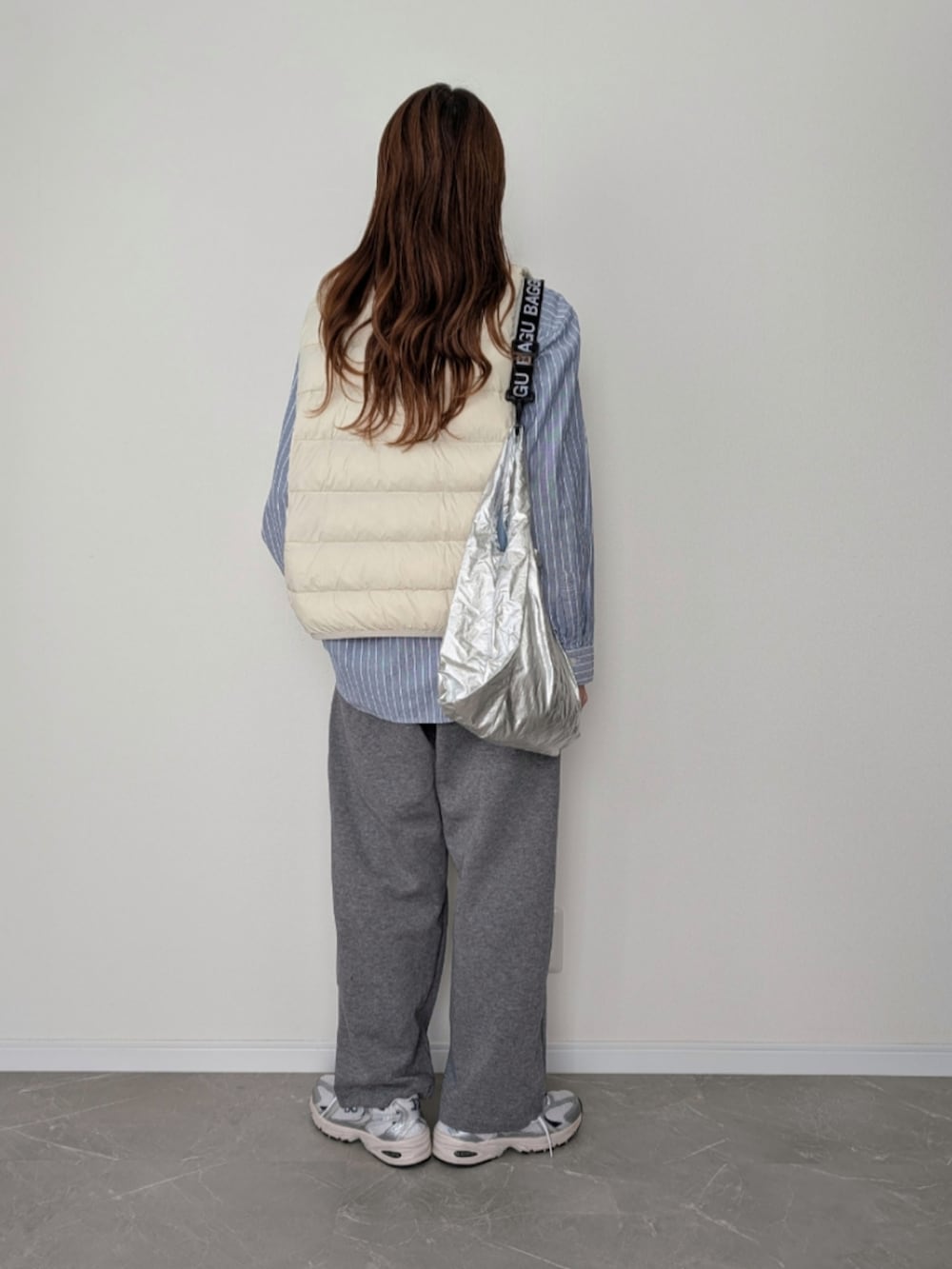 ホワイト系のダウンベスト、グレー系のスウェットパンツ、シルバー系のスニーカーを着用したレディースの秋コーディネートの3枚目の写真