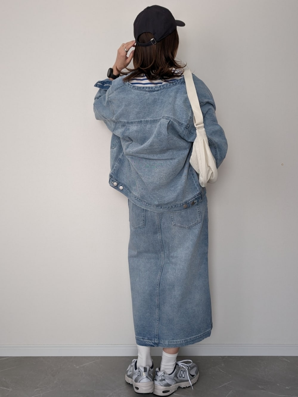 ブルー系のデニムジャケット、ブルー系のスカート、シルバー系のスニーカーを着用したレディースの冬コーディネートの2枚目の写真