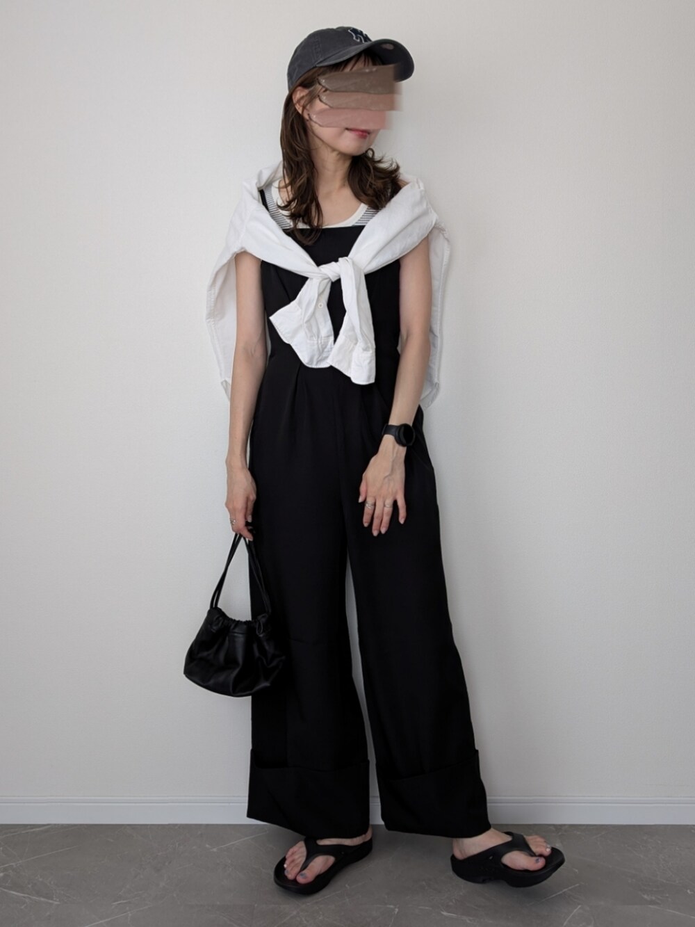 ブラック系のつなぎ/オールインワン、ブラック系のサンダル、グレー系のキャップを着用したレディースの夏コーディネートの2枚目の写真