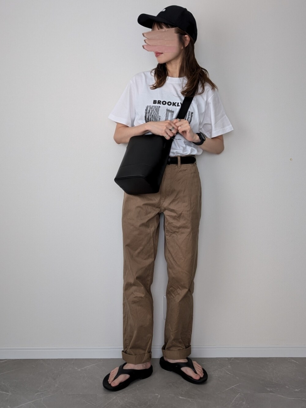 ホワイト系のTシャツ/カットソー、ブラック系のショルダーバッグ、ブラウン系のチノパンツを着用したレディースの夏コーディネートの2枚目の写真
