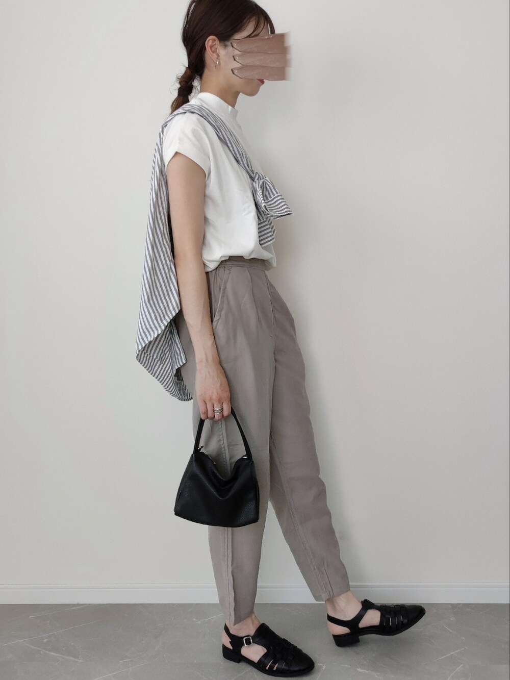 グレー系のスラックス、ホワイト系のTシャツ/カットソー、ブラック系のサンダルを着用したレディースの春コーディネートの2枚目の写真