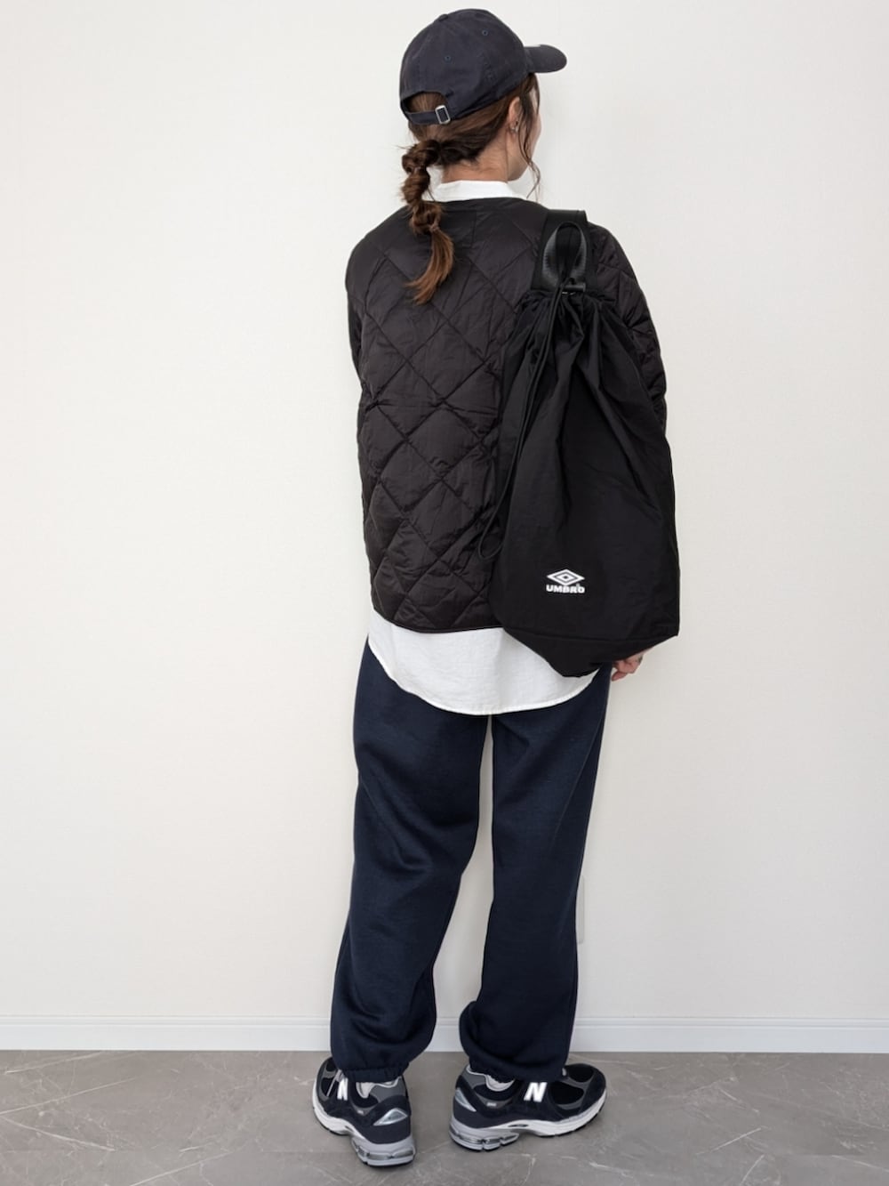 ブラック系のダウンジャケット/コート、ブラック系のバックパック/リュック、ブルー系のスウェットパンツを着用したレディースの冬コーディネートの2枚目の写真