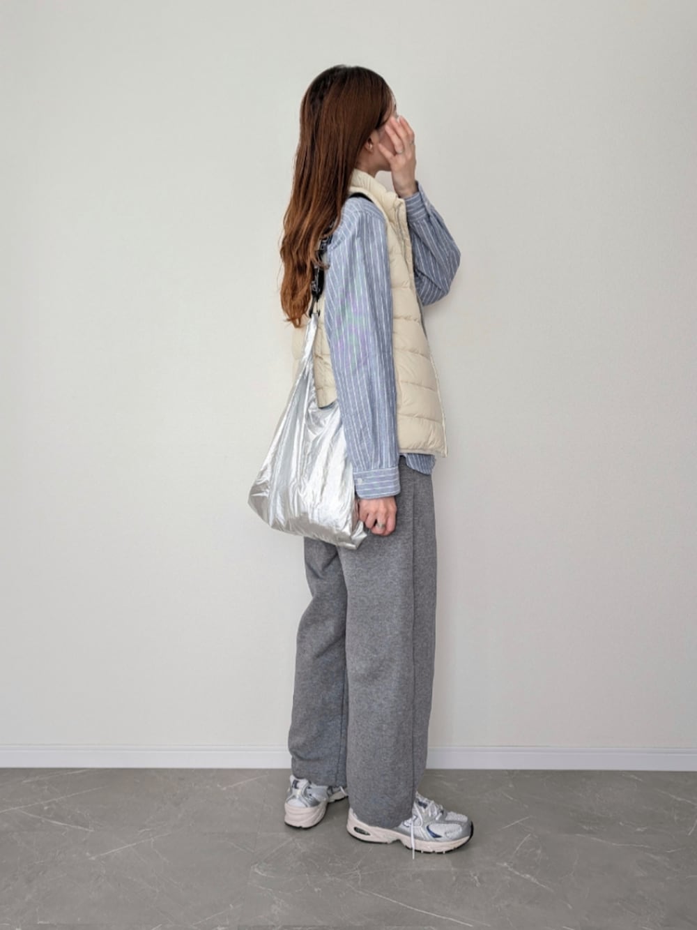 ホワイト系のダウンベスト、グレー系のスウェットパンツ、シルバー系のスニーカーを着用したレディースの秋コーディネートの2枚目の写真