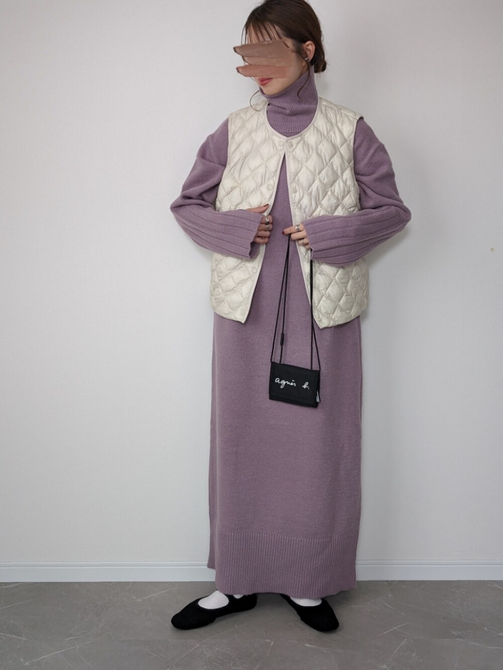 パープル系のワンピース、ブラック系のパンプス、ホワイト系のベストを着用したレディースの冬コーディネートの3枚目の写真