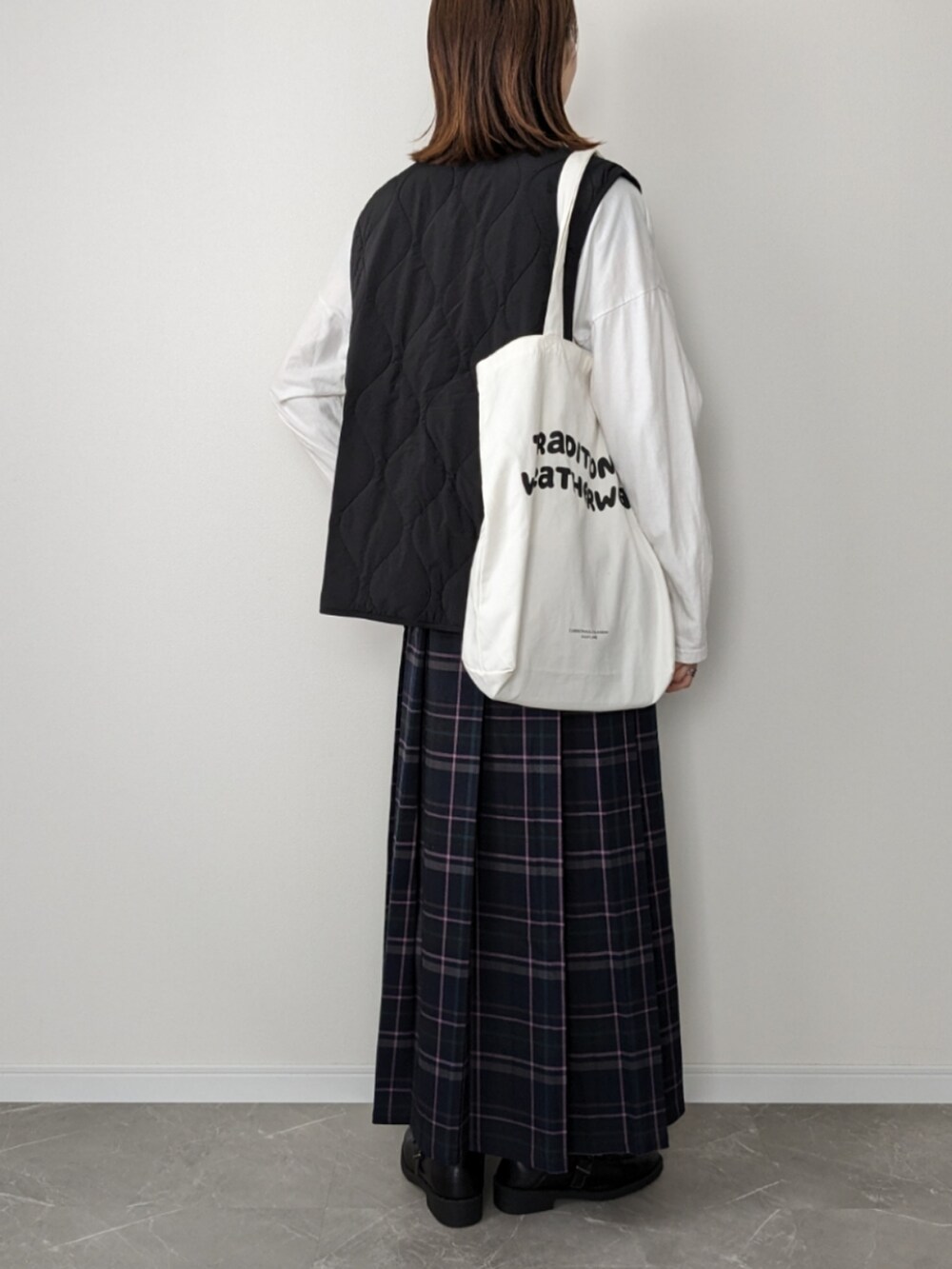 ブルー系のスカート、ブラック系のベスト、ホワイト系のTシャツ/カットソーを着用したレディースの秋コーディネートの2枚目の写真