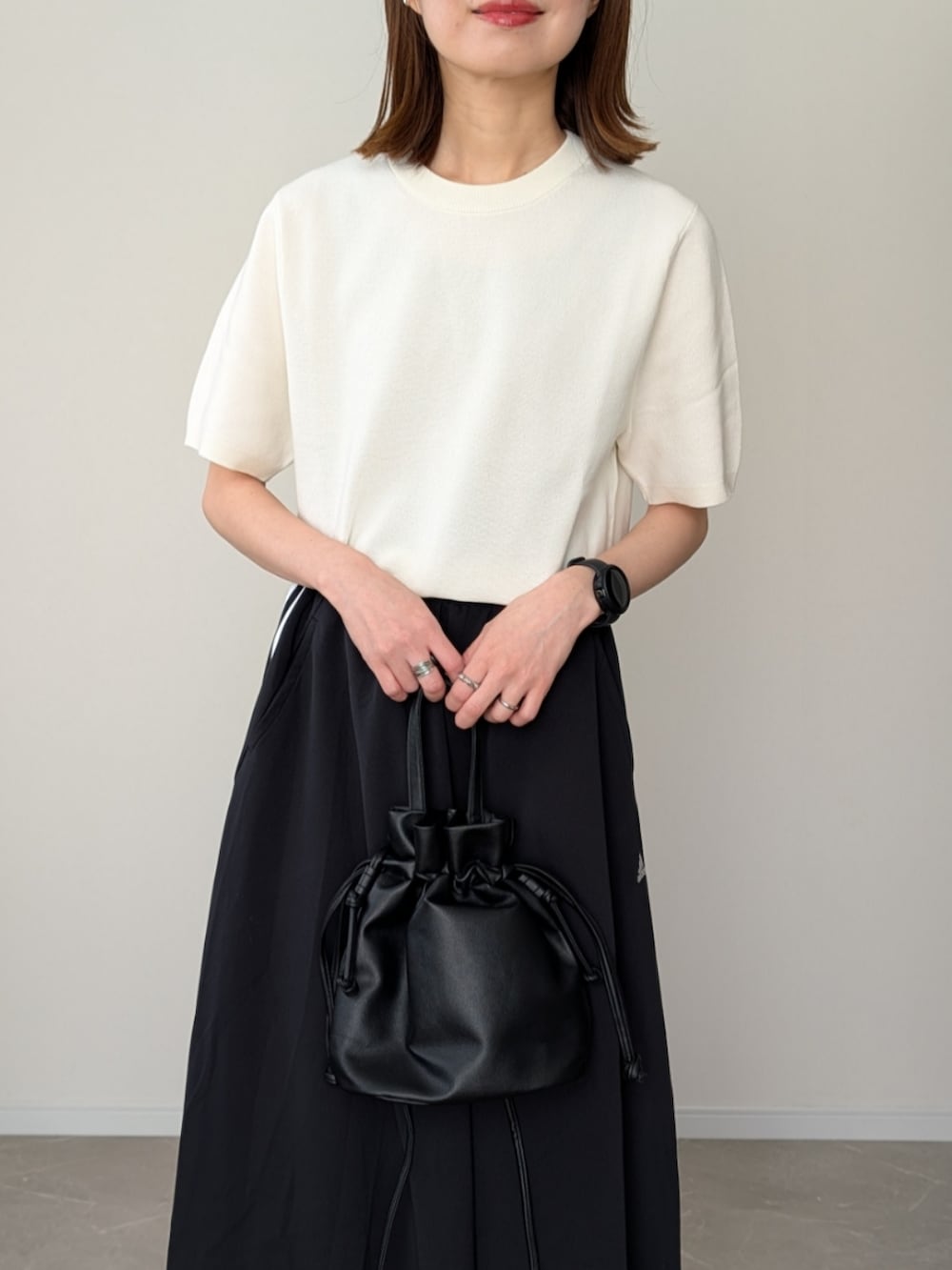 ホワイト系のニット/セーター、ブラック系のスカート、ブラック系のショルダーバッグを着用したレディースの春コーディネートの2枚目の写真