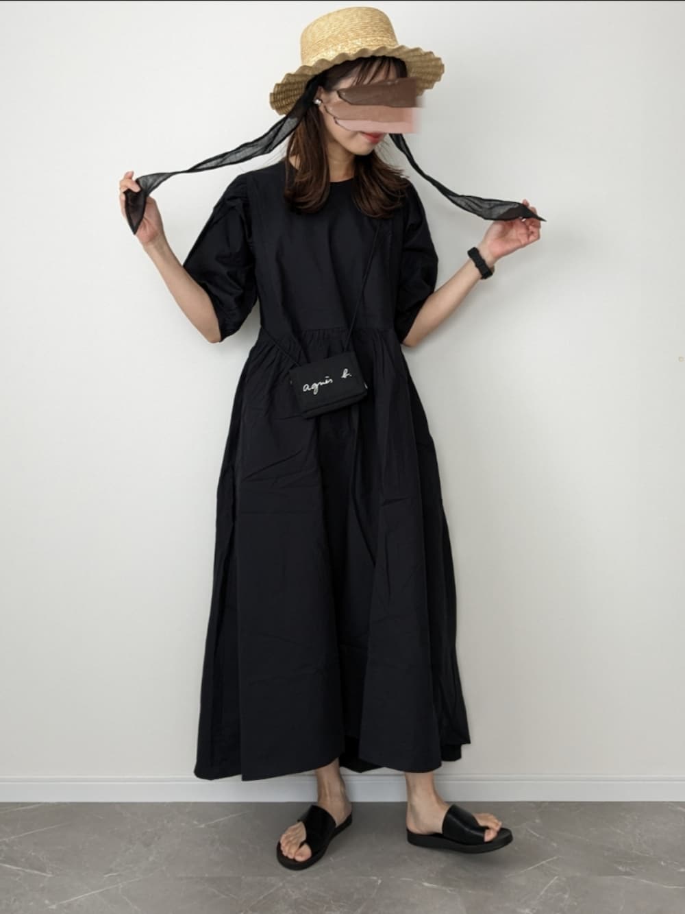 ブラック系のワンピース、ブラック系のサンダル、ベージュ系のハットを着用したレディースの春コーディネートの2枚目の写真