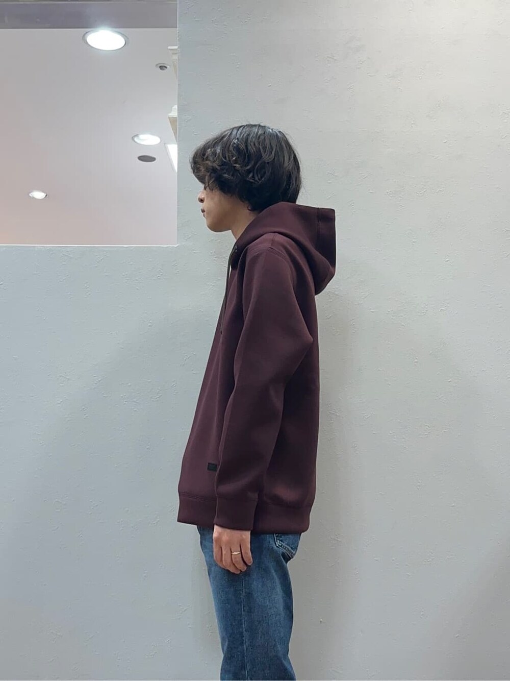 レッド系のパーカー、ブルー系のデニムパンツを着用したメンズの秋コーディネートの4枚目の写真