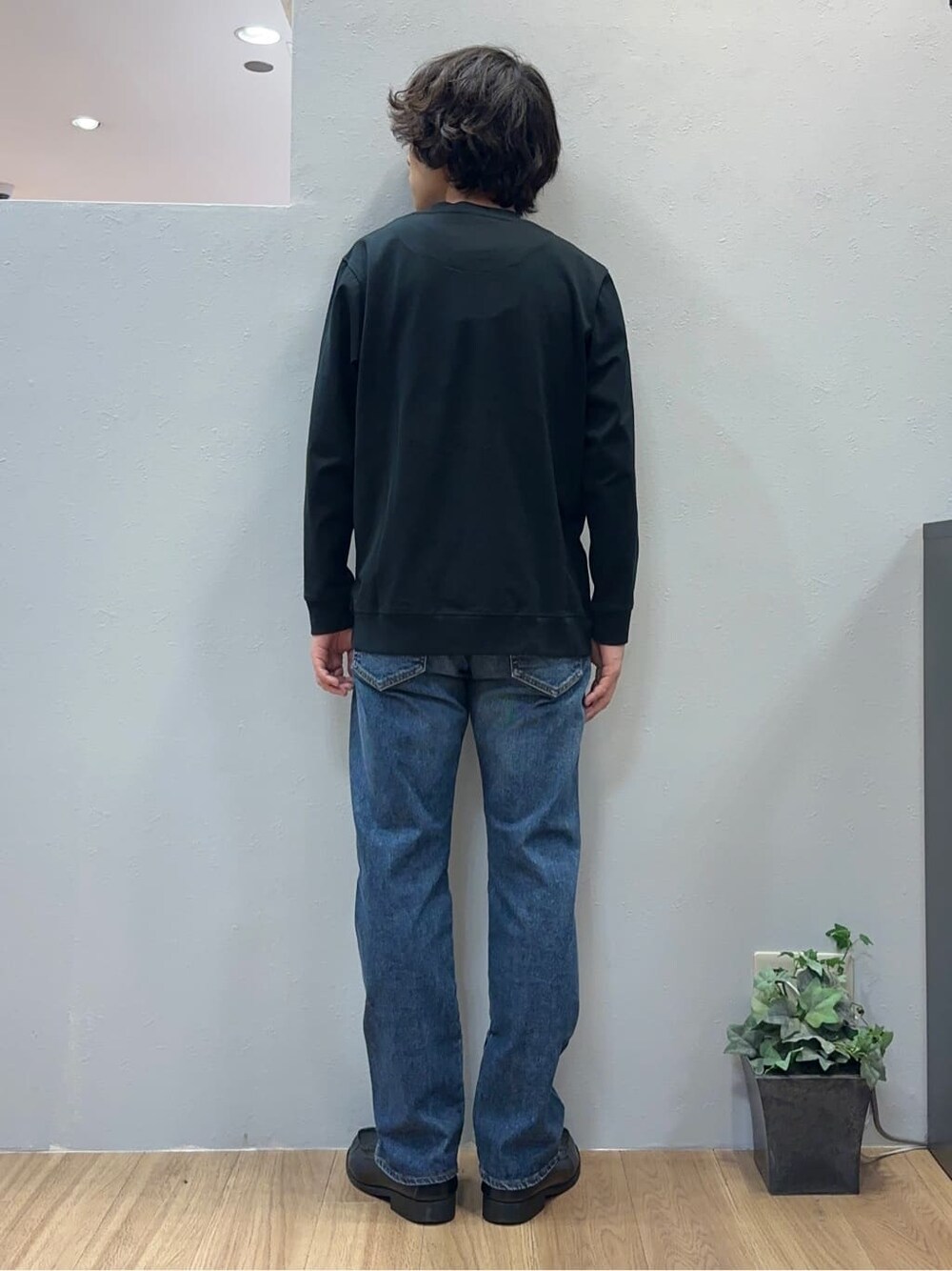 ブルー系のデニムパンツ、グレー系のクラッチバッグを着用したメンズの秋コーディネートの5枚目の写真