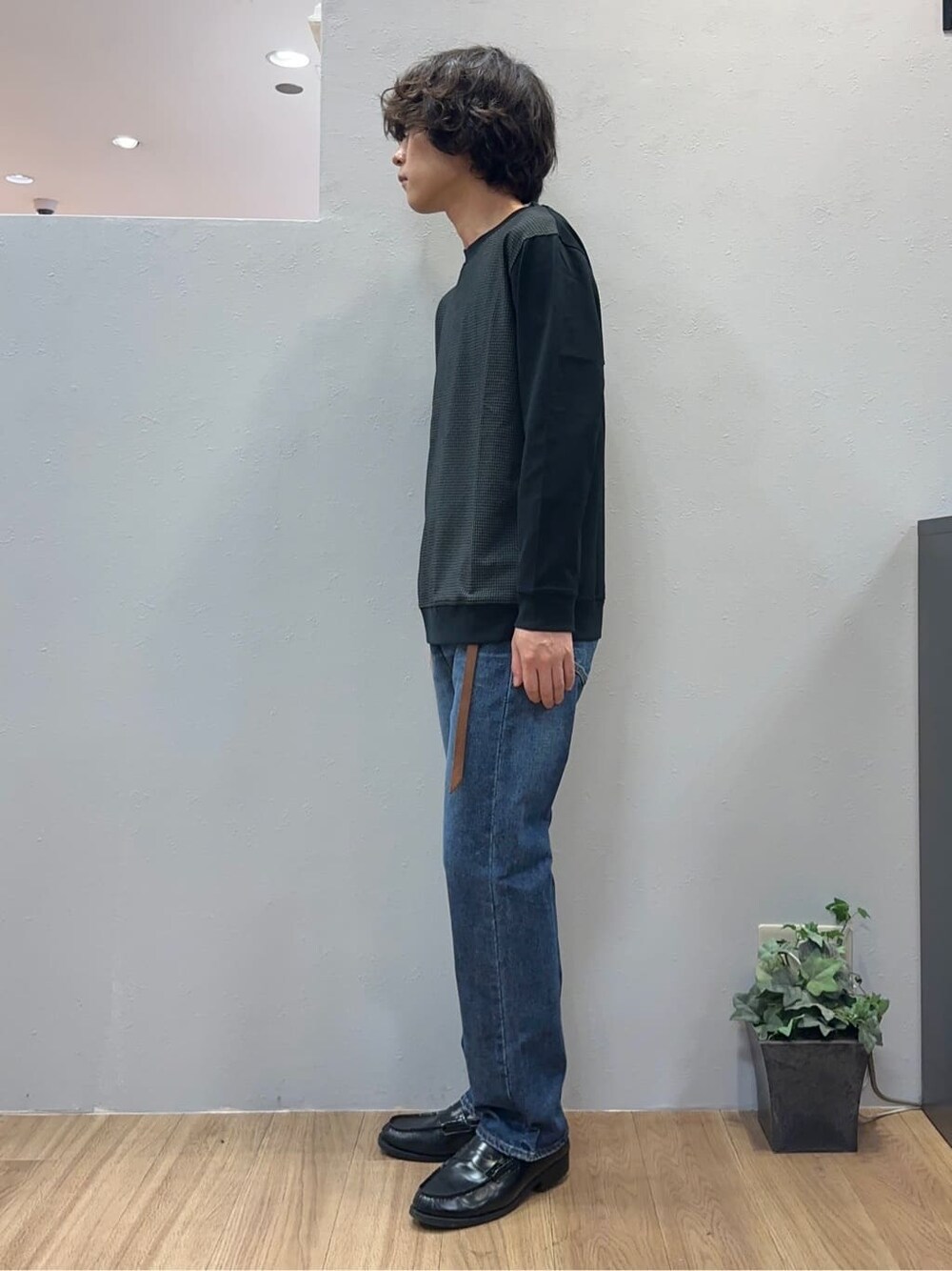 ブルー系のデニムパンツ、グレー系のクラッチバッグを着用したメンズの秋コーディネートの4枚目の写真