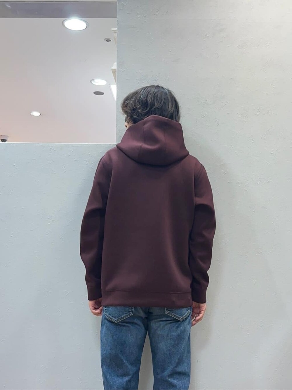 レッド系のパーカー、ブルー系のデニムパンツを着用したメンズの秋コーディネートの5枚目の写真