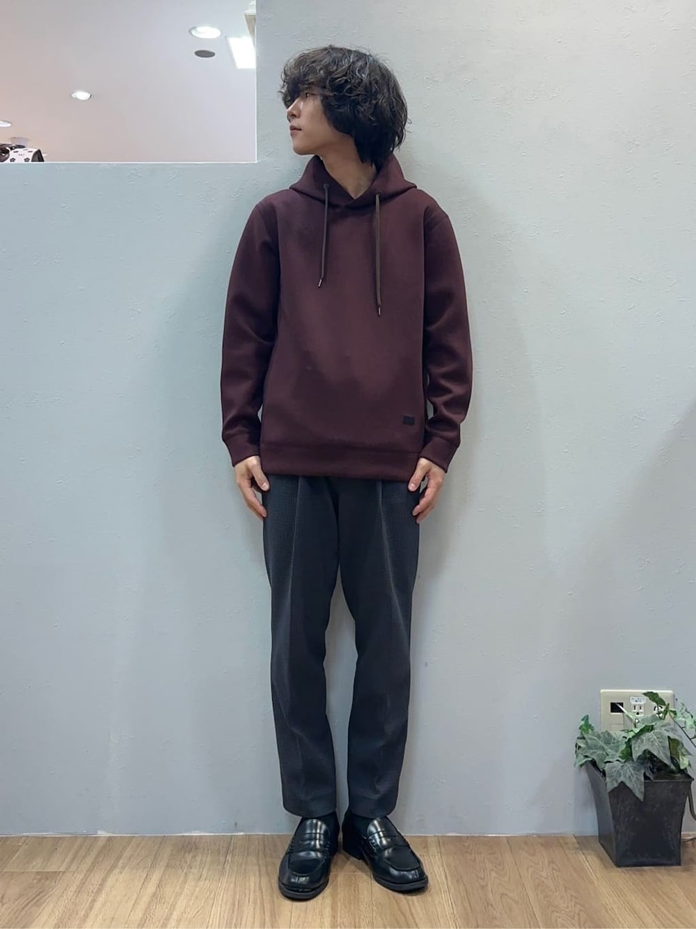 レッド系のパーカー、グレー系のスラックスを着用したメンズの秋コーディネートの3枚目の写真