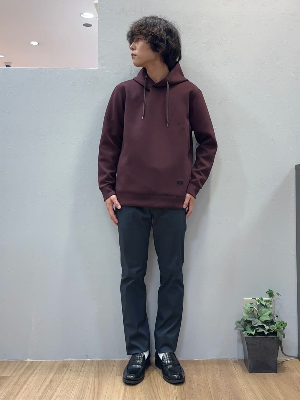 レッド系のパーカー、ブラック系のスラックス、ブルー系のクラッチバッグを着用したメンズの秋コーディネートの4枚目の写真