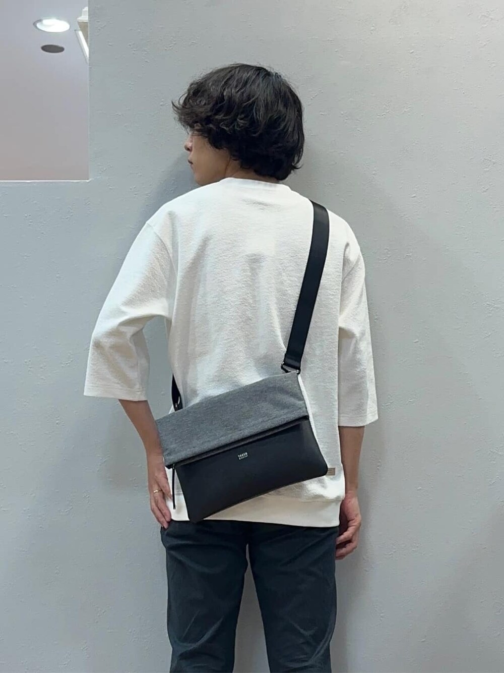 グレー系のスラックス、グレー系のクラッチバッグを着用したメンズの秋コーディネートの3枚目の写真