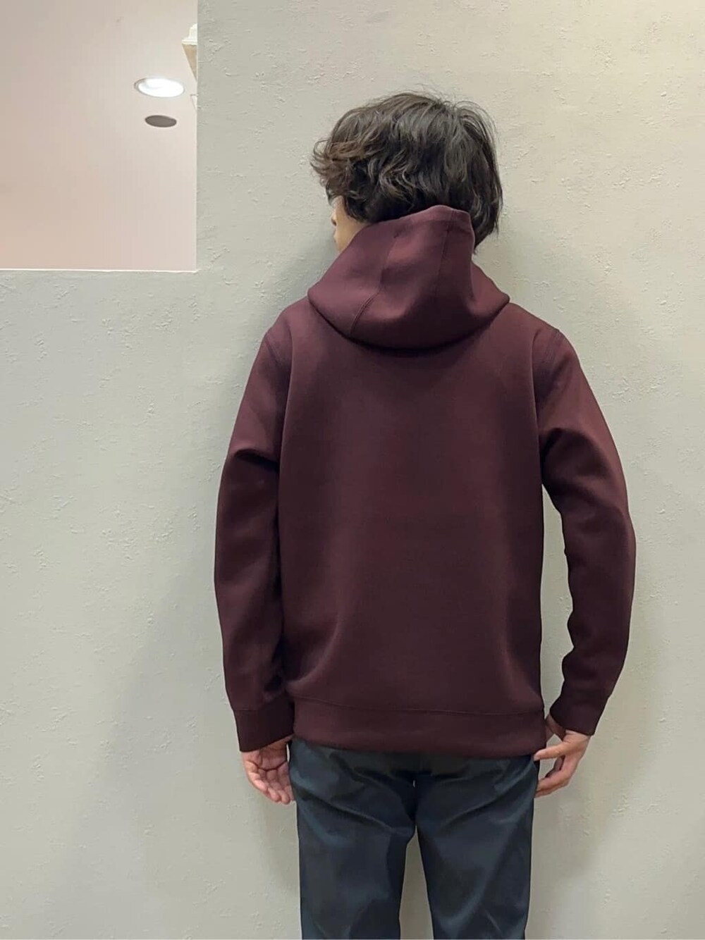 レッド系のパーカー、ブラック系のスラックス、ブルー系のクラッチバッグを着用したメンズの秋コーディネートの6枚目の写真
