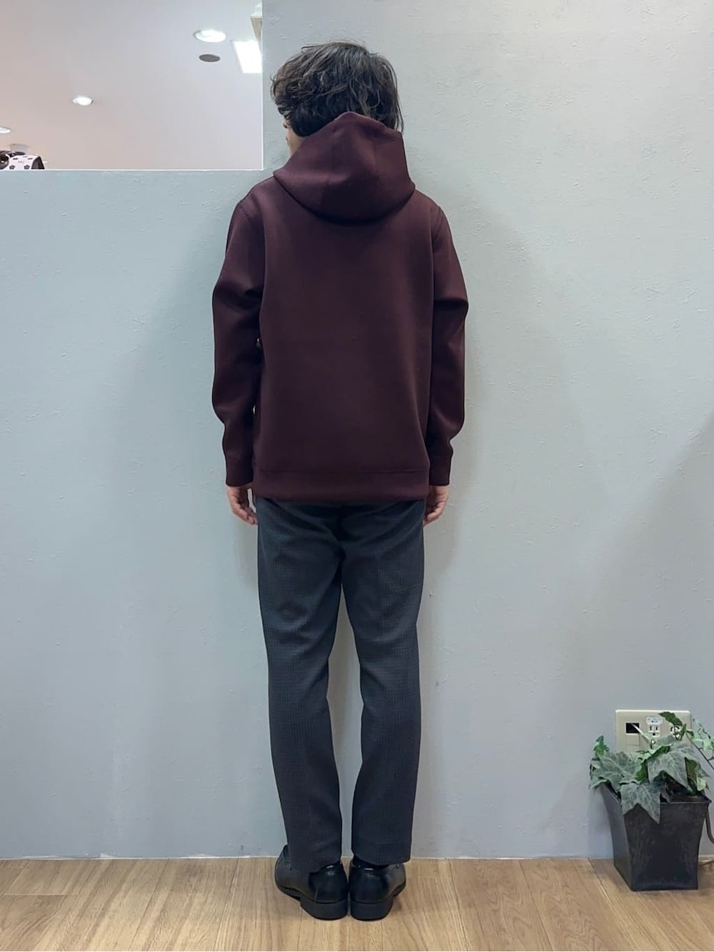 レッド系のパーカー、グレー系のスラックスを着用したメンズの秋コーディネートの5枚目の写真