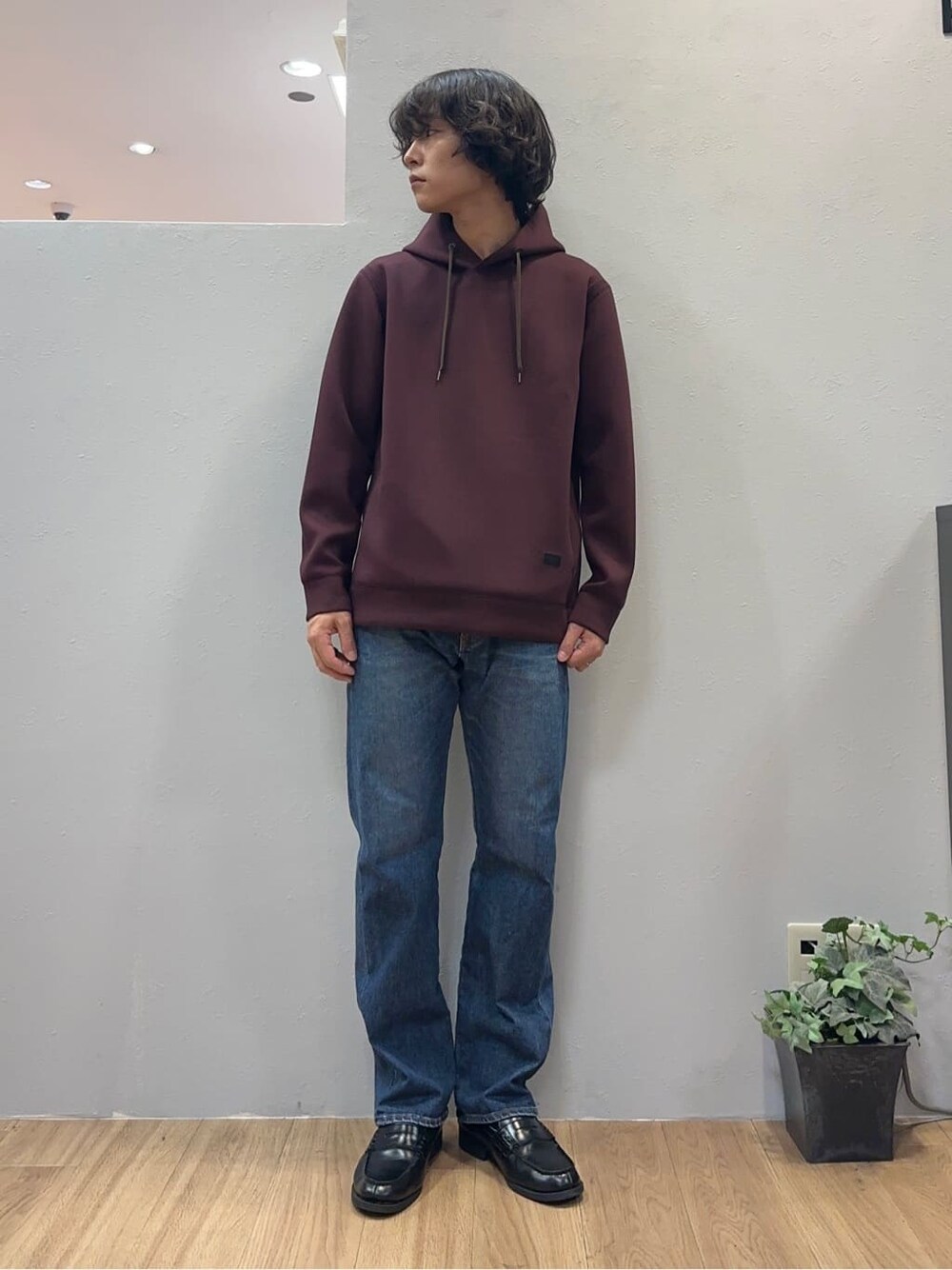 レッド系のパーカー、ブルー系のデニムパンツを着用したメンズの秋コーディネートの3枚目の写真