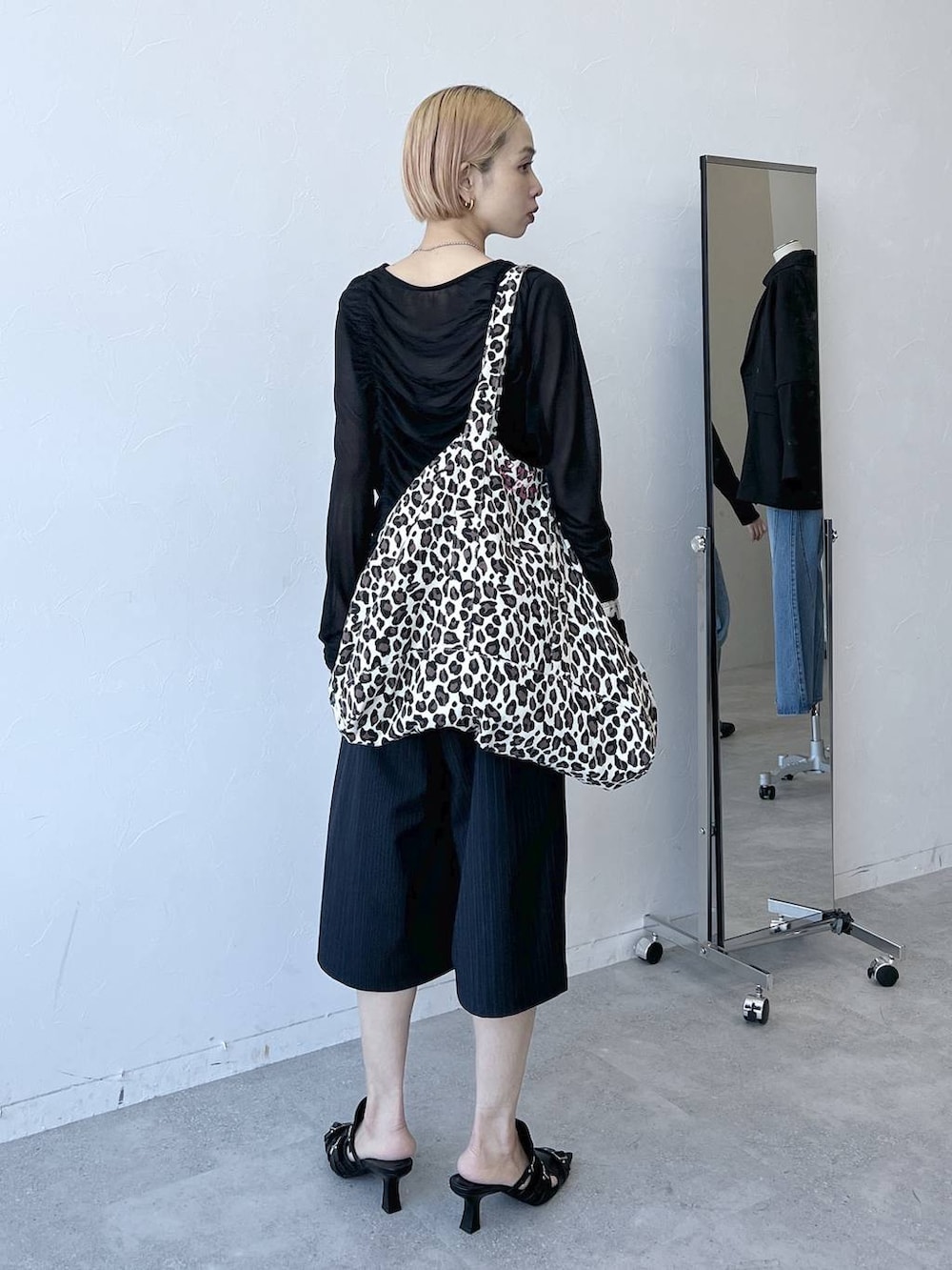 ブラック系のTシャツ/カットソー、ブルー系のスラックス、ブラック系のサンダルを着用したレディースの春コーディネートの5枚目の写真