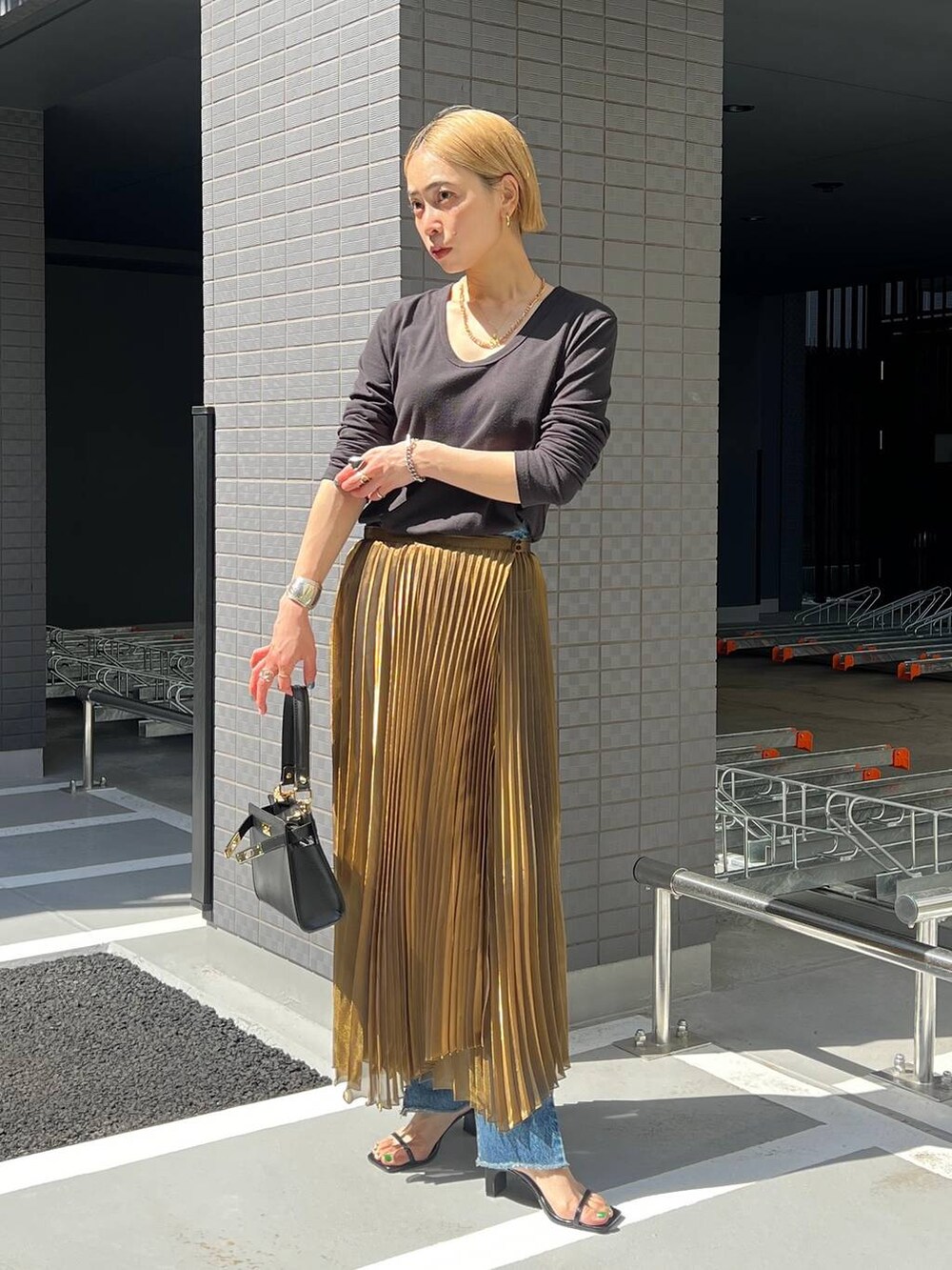 ゴールド系のスカートを着用したレディースの春コーディネートの3枚目の写真