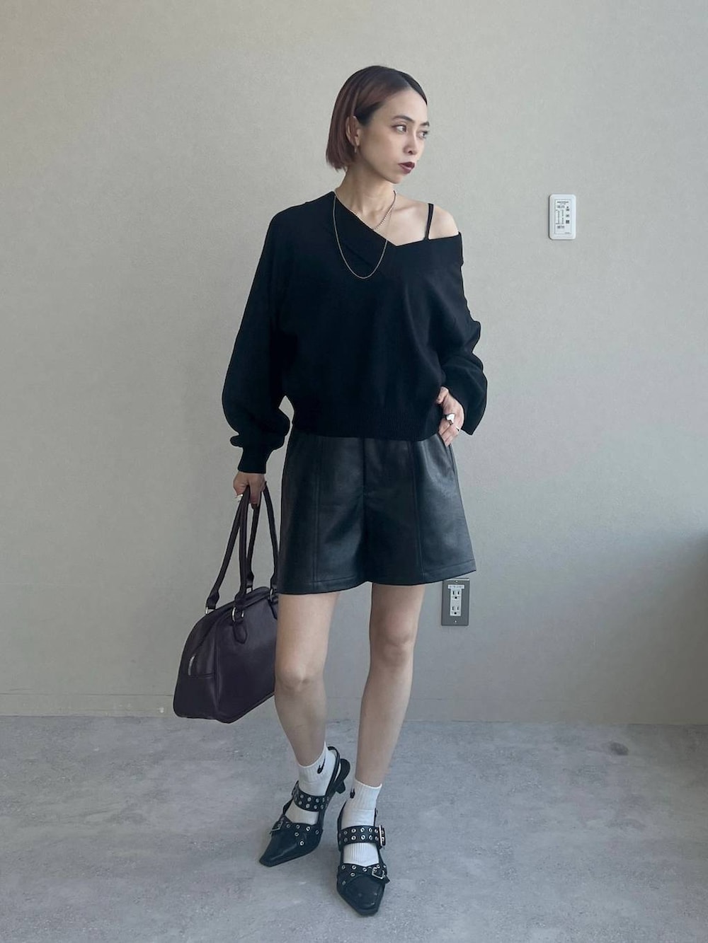 ブラック系のパンプス、レッド系のボストンバッグ、ブラック系のニット/セーターを着用したレディースの秋コーディネートの2枚目の写真