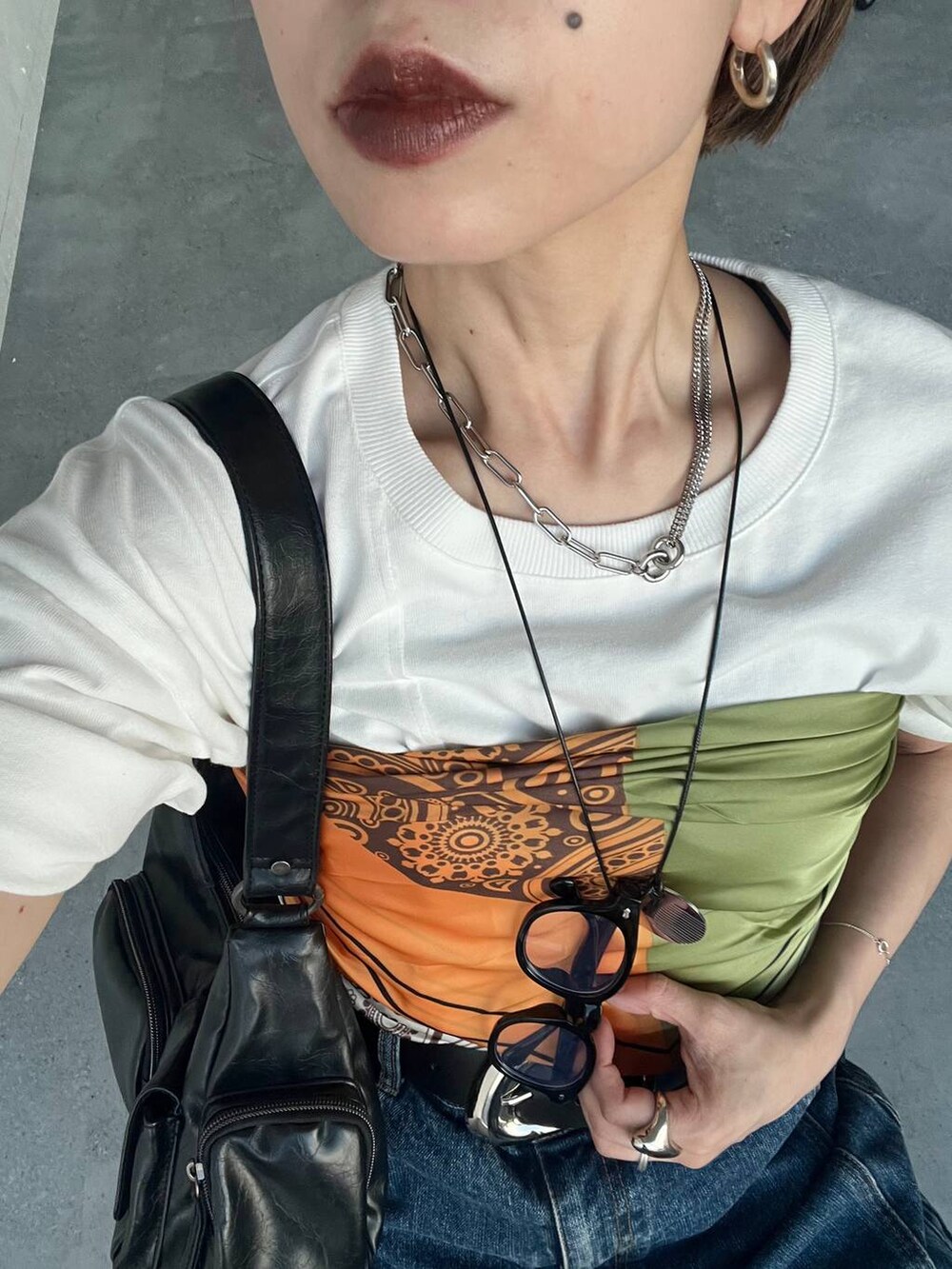 ブラック系のショルダーバッグ、ブラック系のサンダル、ブルー系のデニムパンツを着用したレディースの夏コーディネートの4枚目の写真