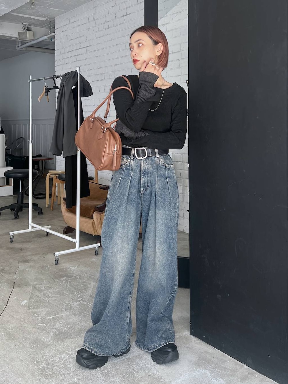 ブラック系のスニーカー、ブルー系のデニムパンツ、イエロー系のボストンバッグを着用したレディースの秋コーディネートの3枚目の写真