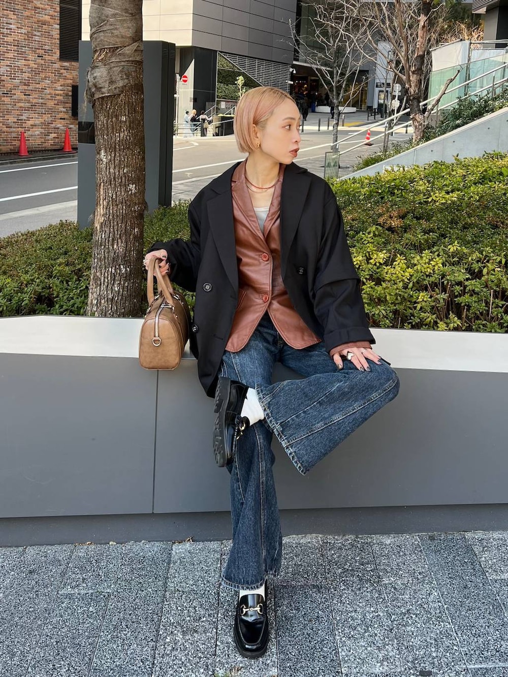 ブルー系のデニムパンツ、ブラウン系のボストンバッグ、ブラック系のテーラードジャケットを着用したレディースの春コーディネートの2枚目の写真