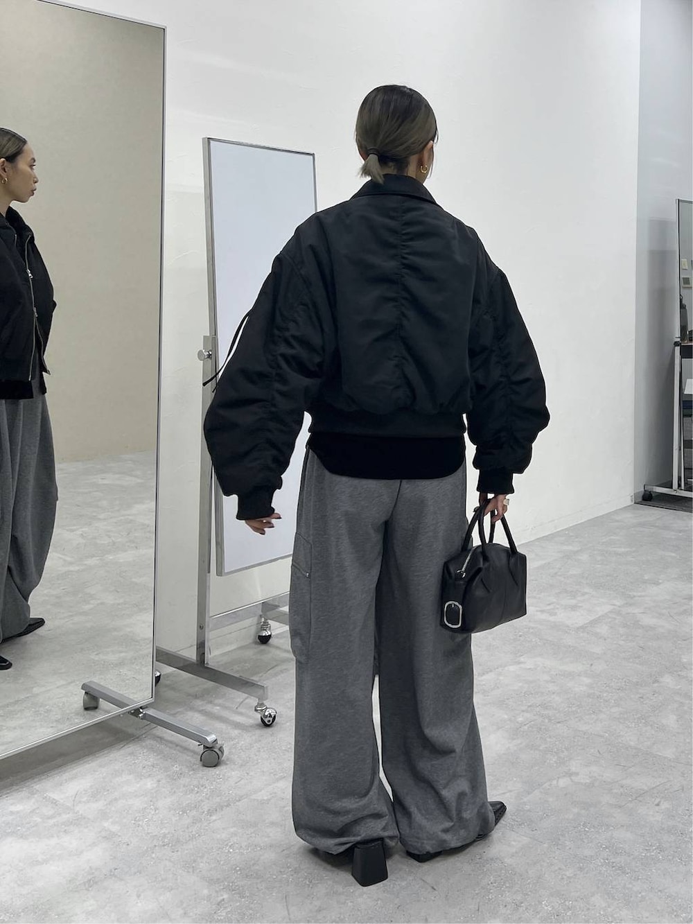 ブラック系のショルダーバッグ、グレー系のスウェットパンツ、ブラック系のMA-1を着用したレディースの秋コーディネートの2枚目の写真