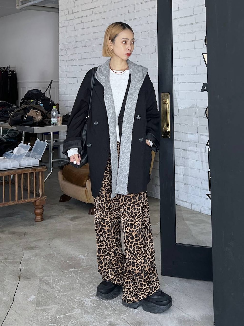 ブラック系のショルダーバッグ、ブラック系のテーラードジャケット、グレー系のマフラーを着用したレディースの秋コーディネートの2枚目の写真