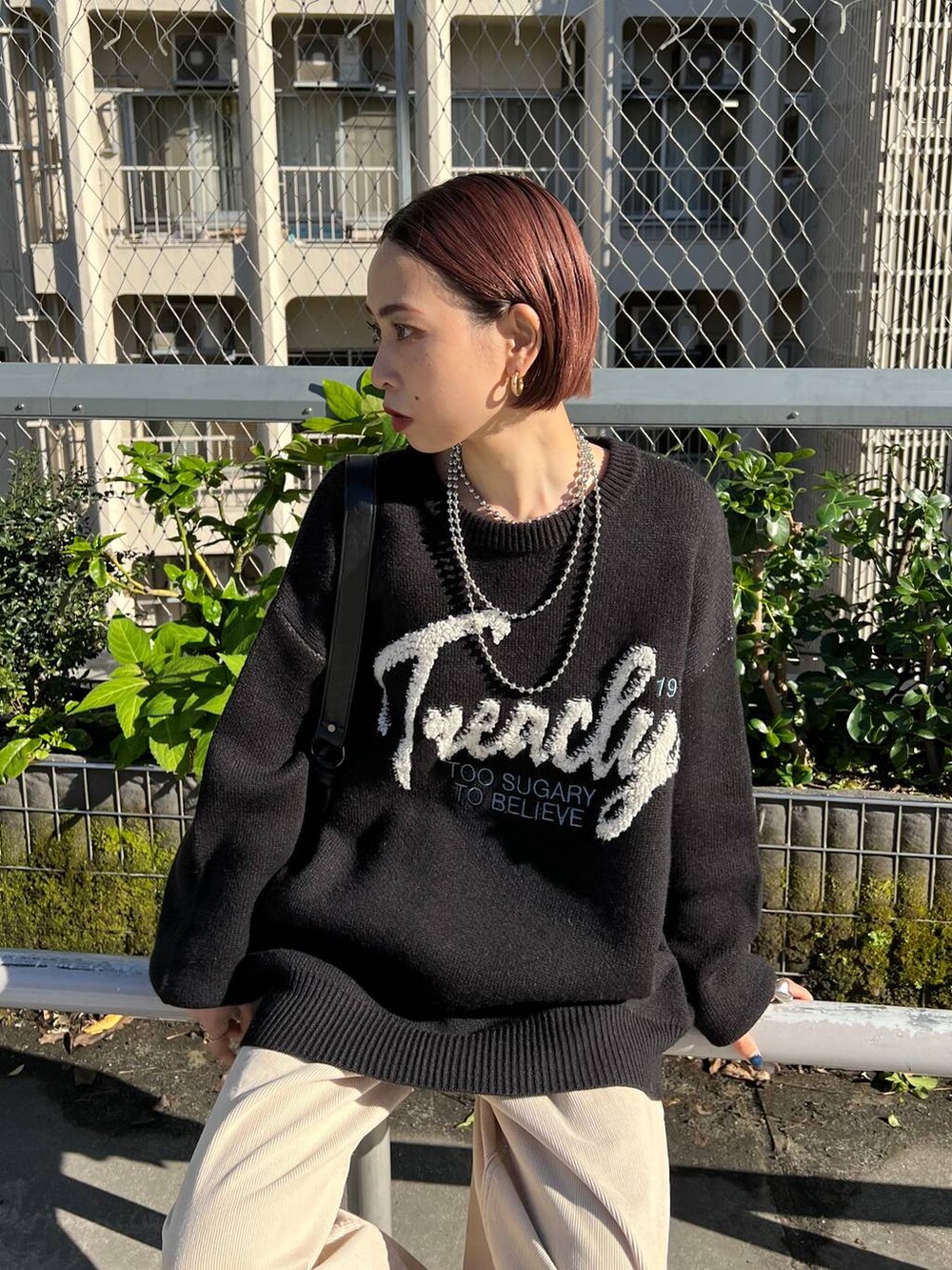 ブラック系のショルダーバッグ、ブラック系のブーツ、ブラック系のニット/セーターを着用したレディースの冬コーディネートの2枚目の写真