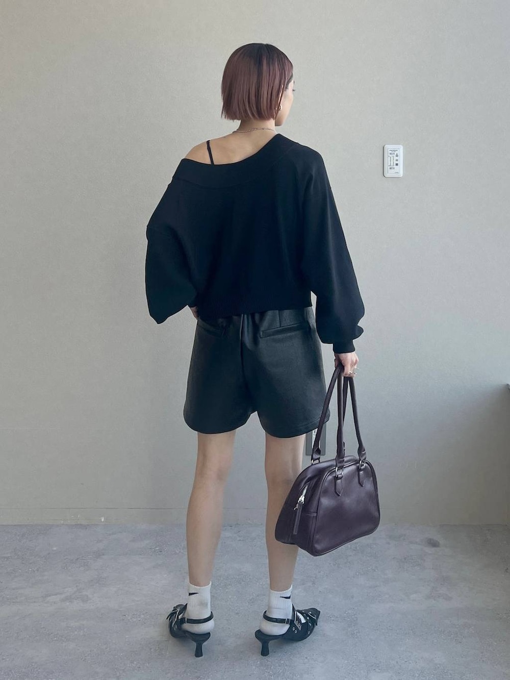 ブラック系のパンプス、レッド系のボストンバッグ、ブラック系のニット/セーターを着用したレディースの秋コーディネートの5枚目の写真