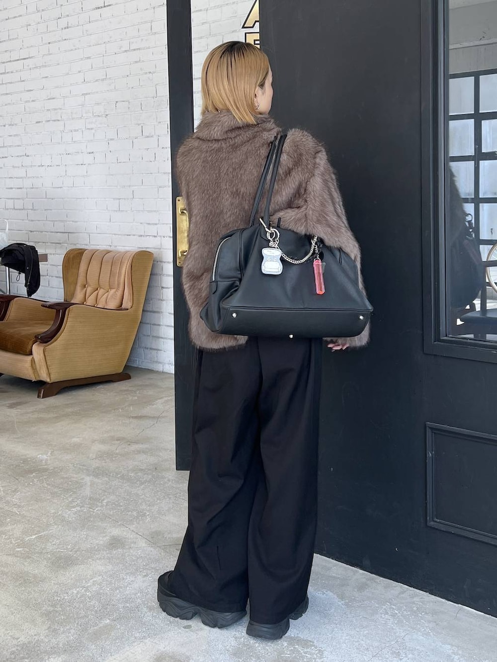 ブラック系のショルダーバッグ、ブラウン系のブルゾンを着用したレディースの秋コーディネートの4枚目の写真